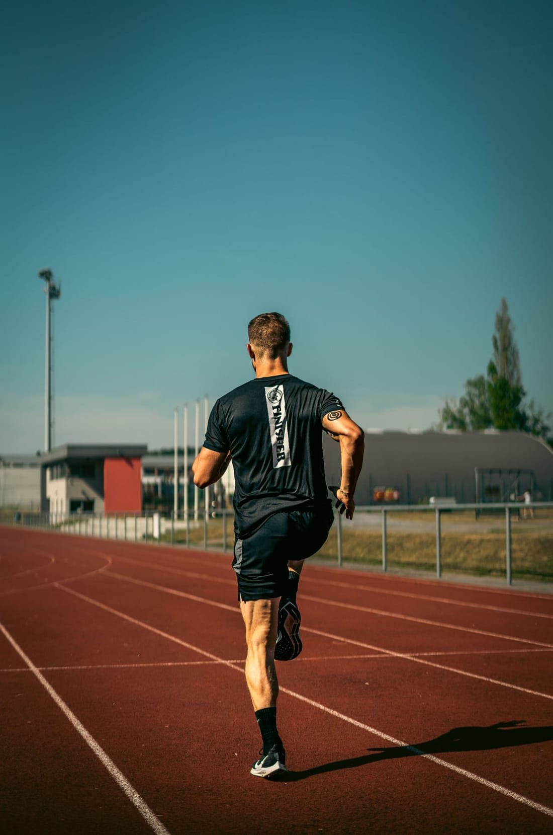 A runner striding out on an athletics track in the sunshine